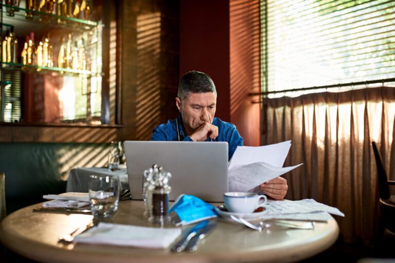 Investor Consider Papers And Laptop While Sitting In Cafe.jpg